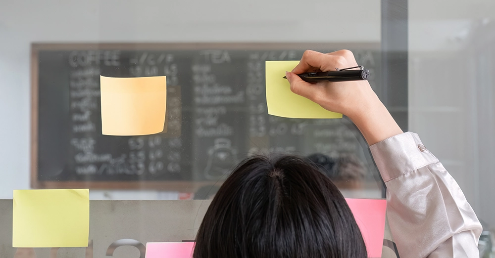 Close-up of an event photographer writing plans on a sticky note during pre-event preparation.